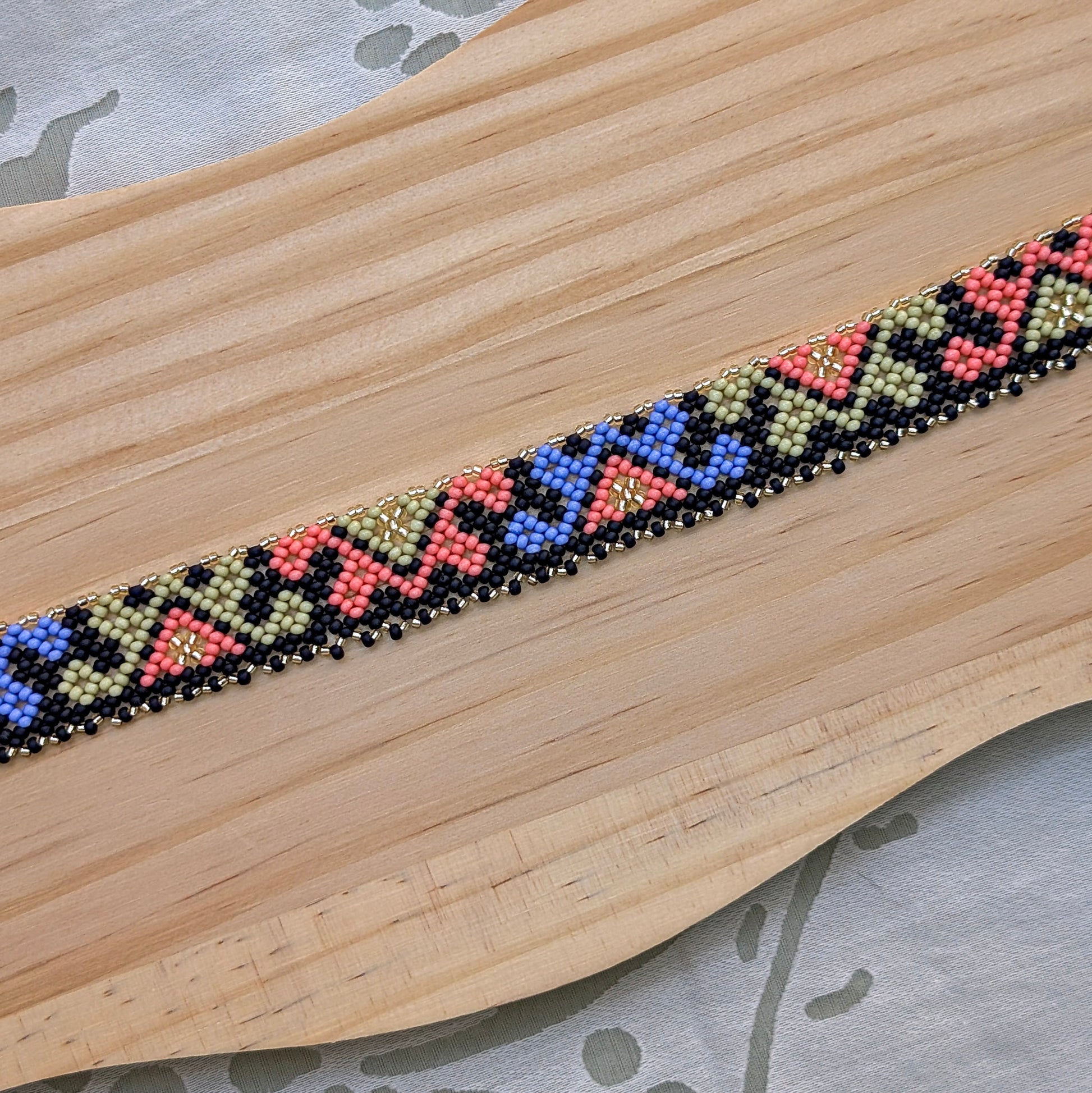 Beaded necklace with geometric pattern on a wooden surface