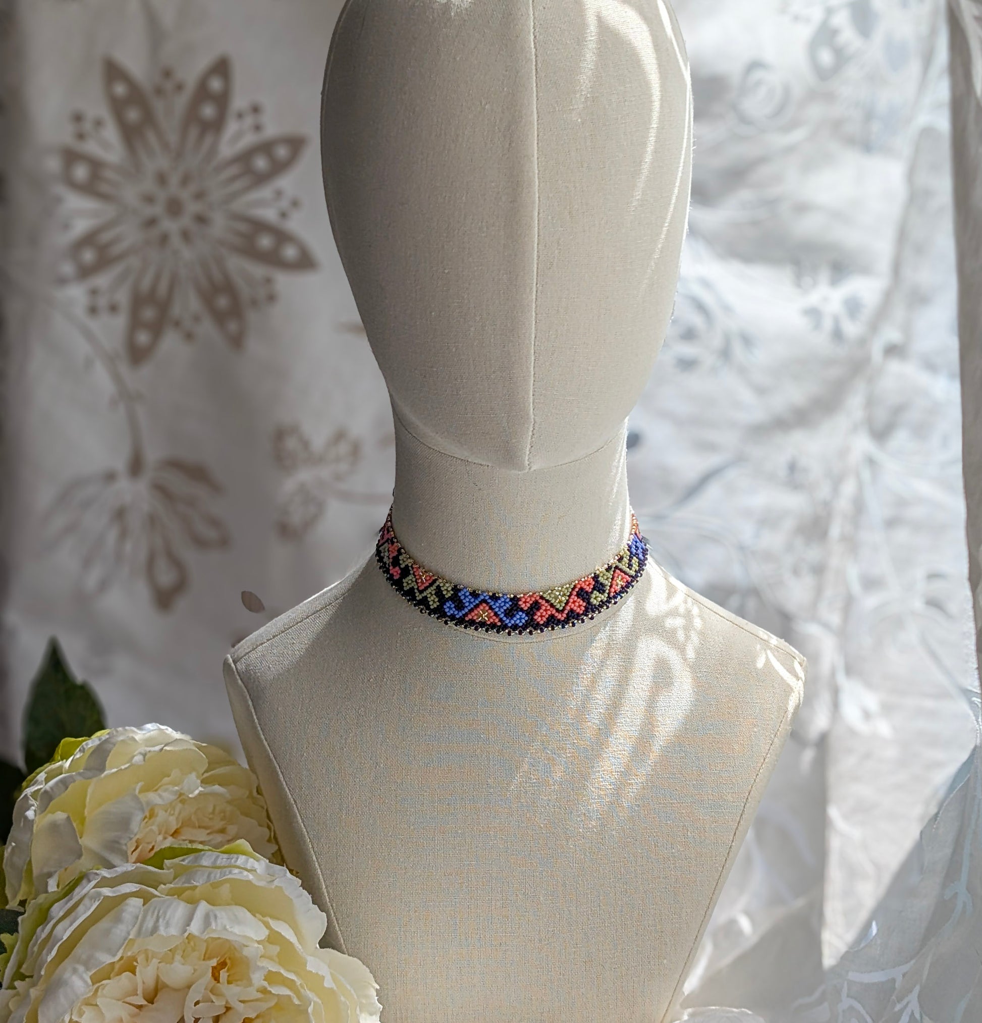 Colorful beaded choker on a mannequin with a floral background