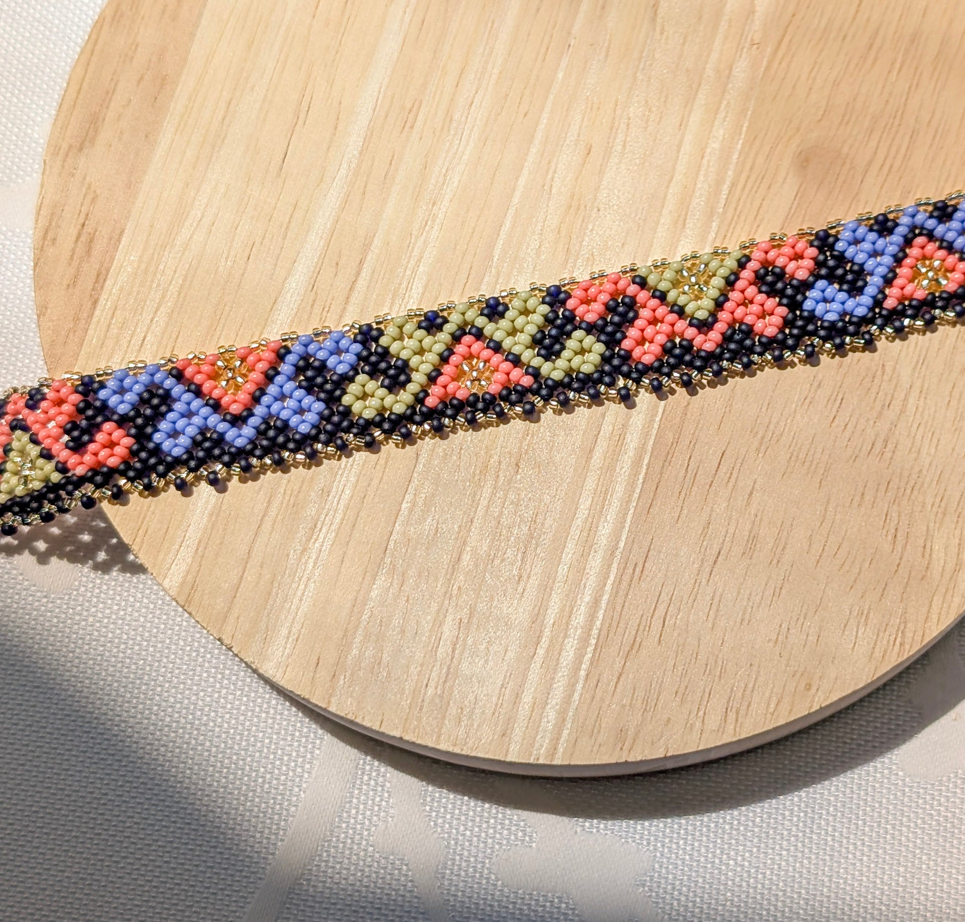 Beaded necklace with geometric pattern on a wooden surface