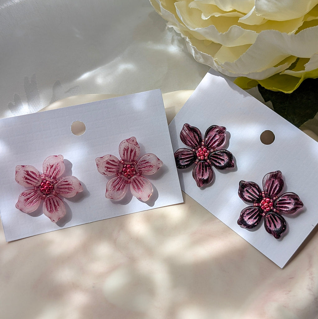 Floral earrings on white cards with a floral background.