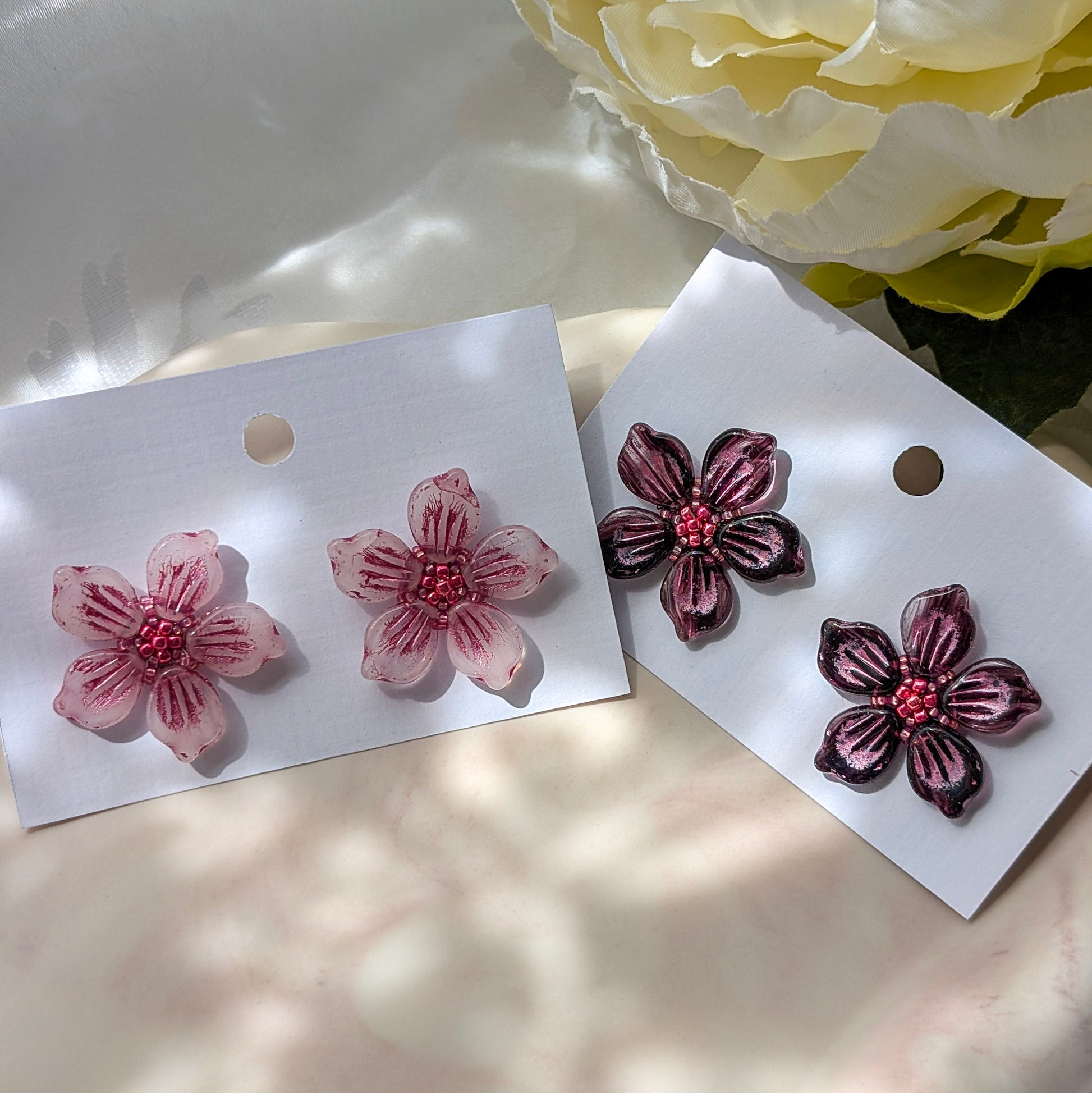 Floral earrings on white cards with a floral background.
