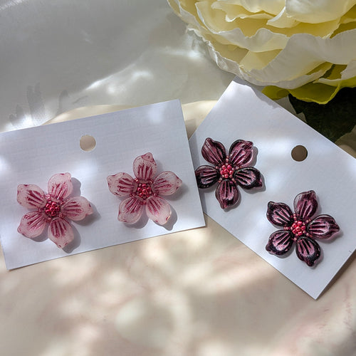 Floral earrings on white cards with a floral background.