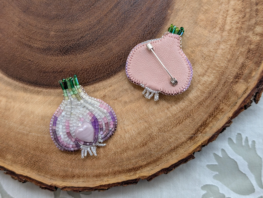 Two beaded brooches on a wooden surface, one of them is backside up